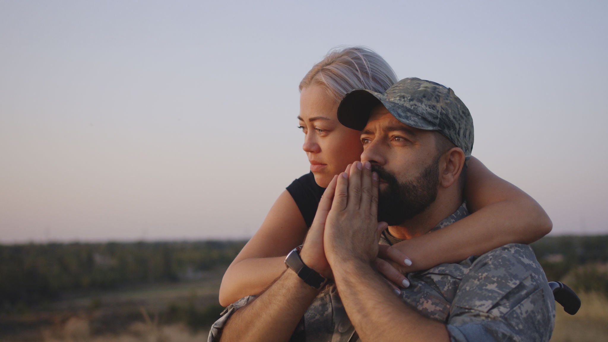 Medium close-up of wife hugging wheelchaired soldier husband