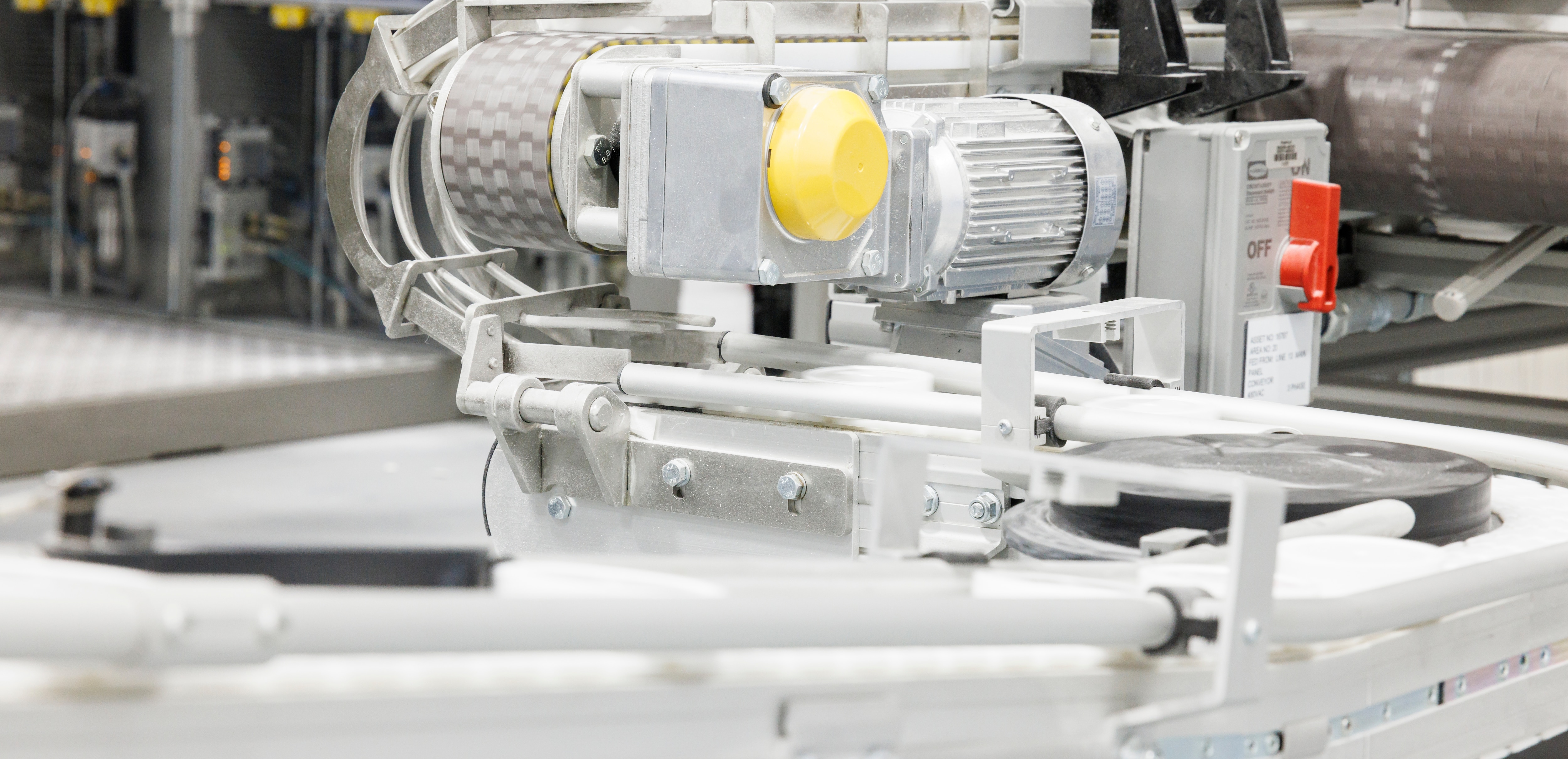 Close-up of industrial machinery with a motor and conveyor system, featuring metal components and a clean, modern design.