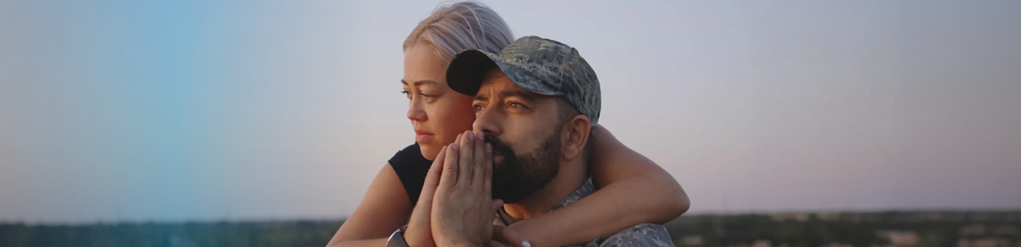 Medium close-up of wife hugging wheelchaired soldier husband